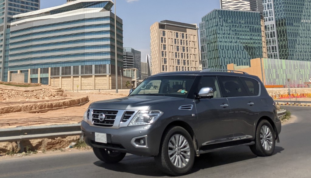 A gray luxury SUV driving on a city street.