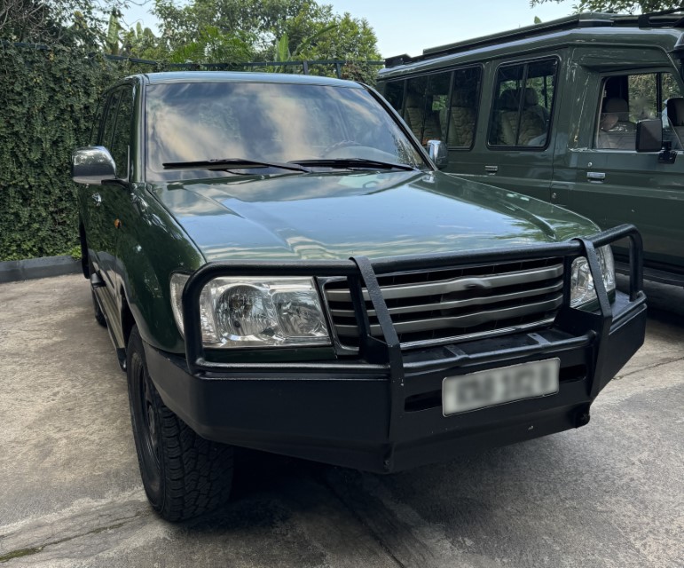 A dark green SUV with a front bull bar, parked on a concrete surface.