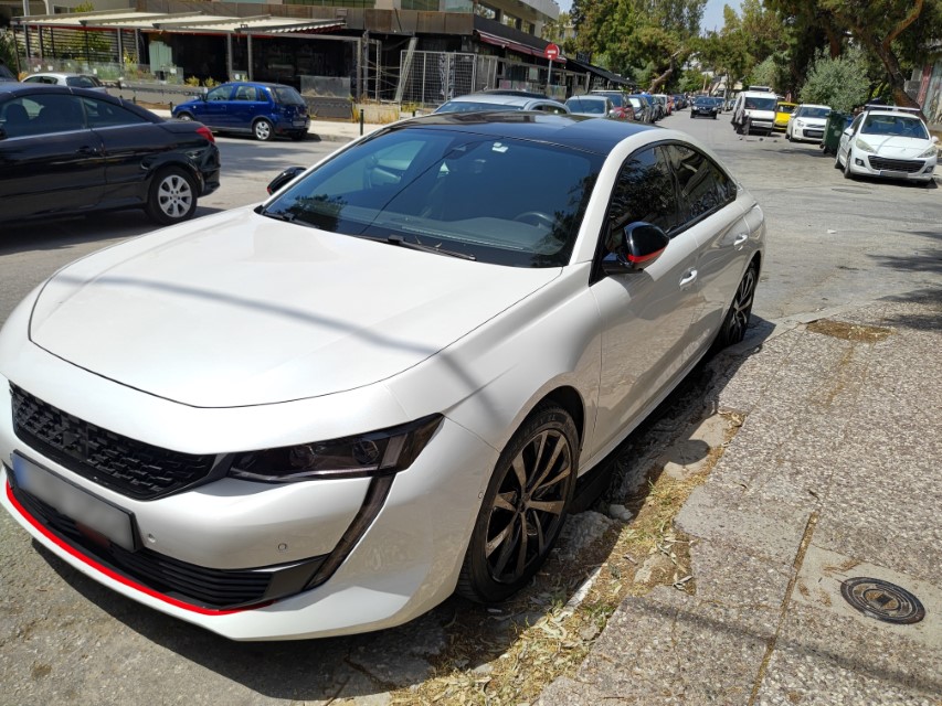 A modern white sedan, parked on a street.
