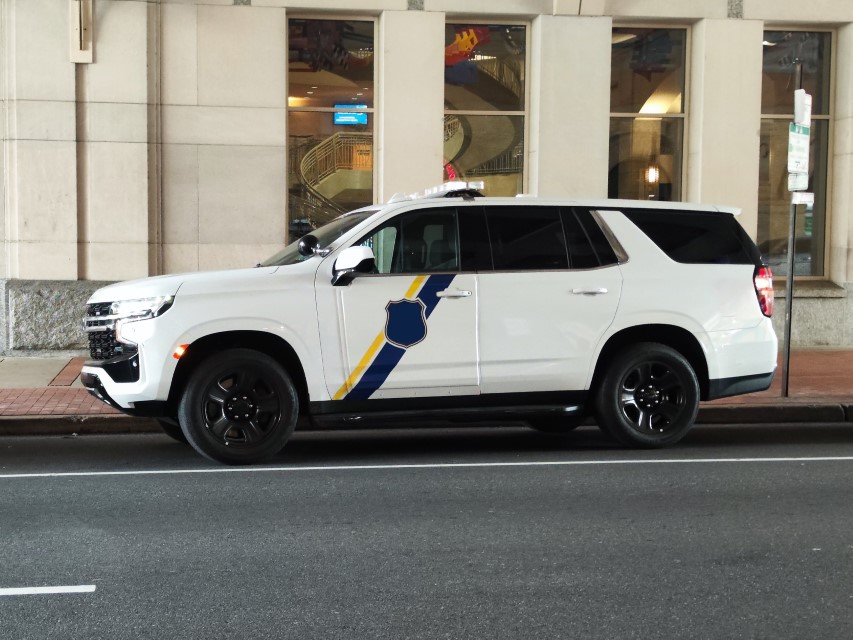 A white SUV with official markings, parked in front of a large building.