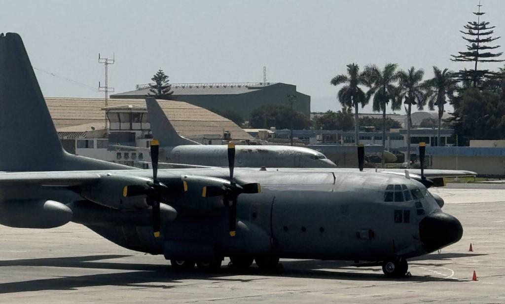 A grey military transport aircraft with propellers parked on an airfield.