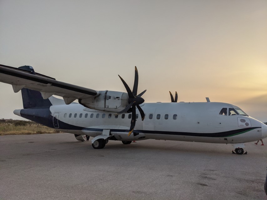 A white twin-propeller aircraft parked on the tarmac.