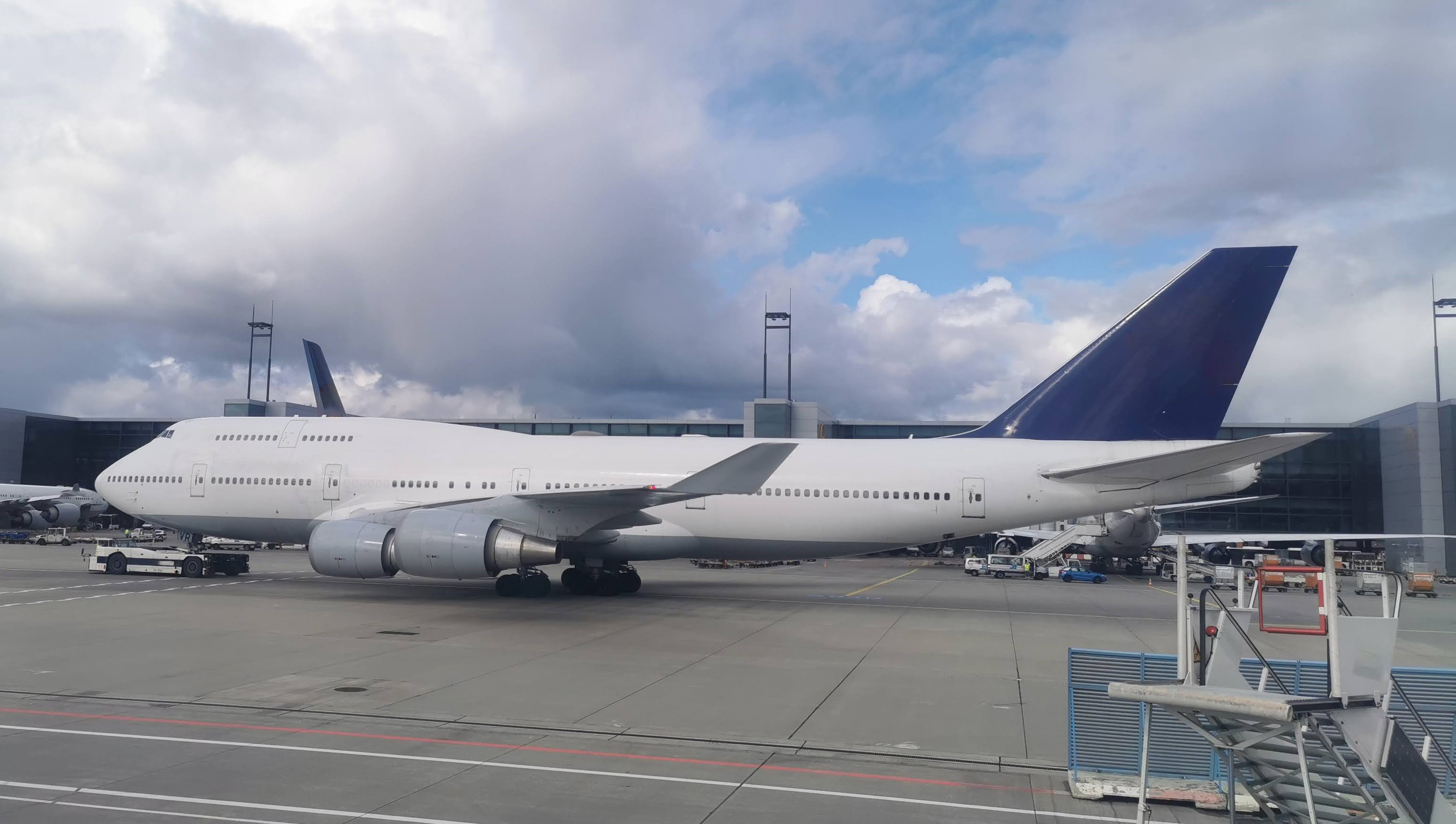 A large white passenger airplane with a blue tail parked at an airport.