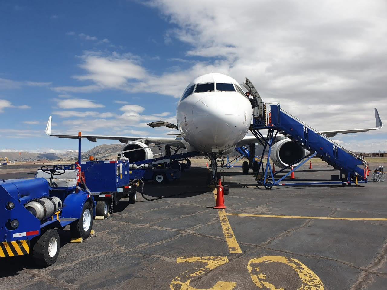 A white airplane parked on a runway with stairs positioned for boarding.