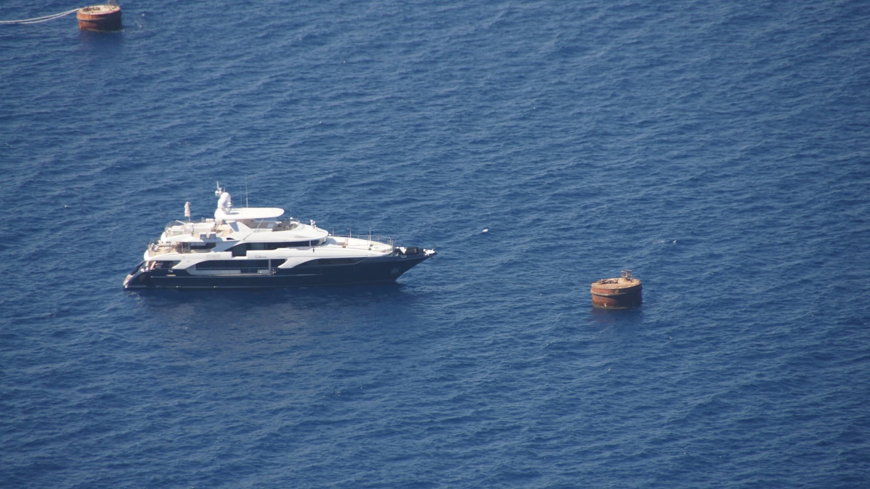 A luxurious white yacht anchored in calm blue waters.