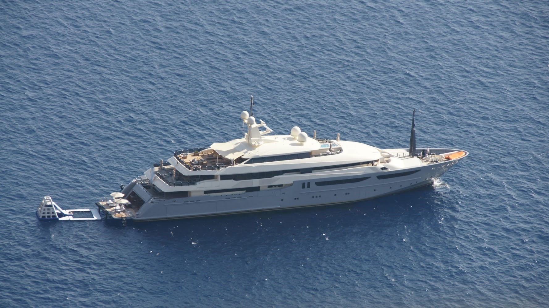 A white yacht with multiple decks floating in the ocean.