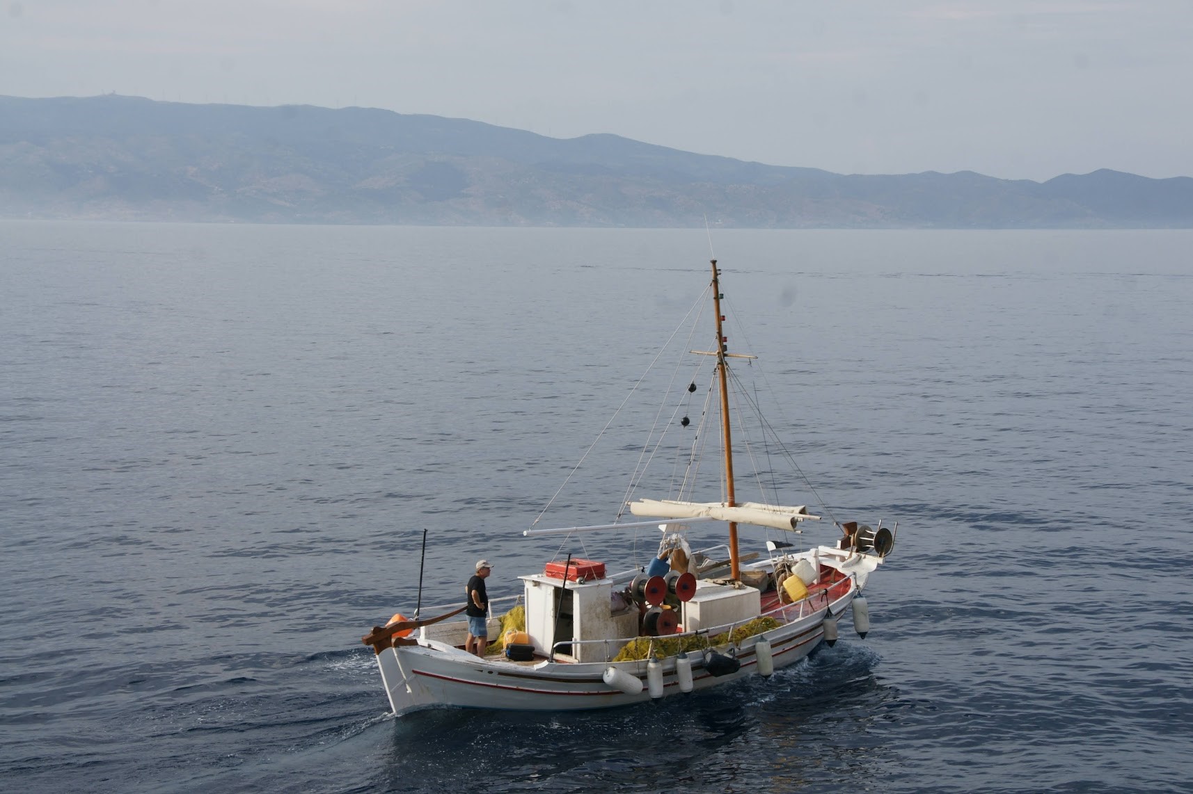 A small traditional fishing boat with a mast and nets.